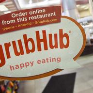 A sign with the old Grubhub logo is displayed is displayed on the door to a New York restaurant. 