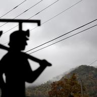 In this Oct. 16, 2014 file photo, fog hovers over a mountaintop as a cutout depicting a coal miner stands at a memorial to local miners killed on the job in Cumberland, Ky. 