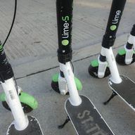 Sharable electric scooters under brand name Lime, by the micro-mobility company Neutron Holdings, Inc., wait on sidewalks for pedestrian use.