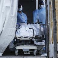 Medical workers wearing personal protective equipment intake bodies through a tent before loading them onto a refrigerated trailer serving as a makeshift morgue at Wyckoff Heights Medical Center.