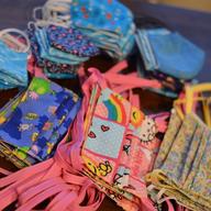 neat piles of homemade cloth medical masks, of various colorful prints and patters.