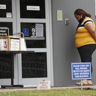 A woman, holding an unemployment application, speaks with an unseen state worker via intercom outside this state WIN job center in Canton, Miss., Wednesday, April 29, 2020.