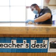 Des Moines Public Schools custodian Joel Cruz cleans a teacher's desk in a classroom at Brubaker Elementary School, Wednesday, July 8, 2020, in Des Moines, Iowa.