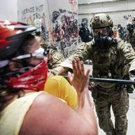 A federal officer pushes back demonstrators at the Mark O. Hatfield United States Courthouse on Tuesday, July 21, 2020, in Portland, Ore.
