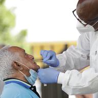 Lab technician James Donald, right, uses a nasal swab to test Hugo Marti for COVID-19, Tuesday, July 28, 2020, at the AHEPA Apartments in Miami.