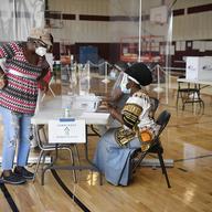 Christine Shannon, left, checks in to vote with volunteer Patricia Nelson, right, at Rawson Elementary School, Tuesday, Aug. 11, 2020, in Hartford, Conn.