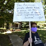A protester stands outside the house of Senate Majority Leader Mitch McConnell, R-Ky., in Louisville, Ky., Saturday, Sept. 19, 2020. McConnell vowed on Friday night, hours after the death of Ginsburg.