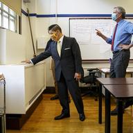 School Chancellor Richard Carranza, left, feels for airflow from a ventilation unit inside a classroom at Bronx Collaborative High School, during a visit with Mayor Bill de Blasio, right, to review he