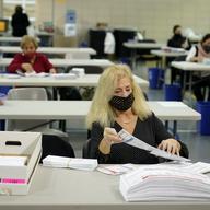 Linda Aftab works with other seasonal Board of Election employees to prepare mail-in ballots for counting in Linden, N.J., Thursday, Oct. 29, 2020. 