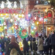 A house decorated for Christmas with a crowd of people enjoying the lights.