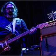 Yo La Tengo's guitar player plays guitar next to an amp with a menorah on top of it.