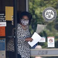 In this April 21, 2020 file photo, a worker wearing a mask to protect against coronavirus, holds an unemployment benefit application form as she waits for a client at the state WIN job center in Miss.