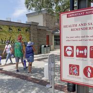 In this June 16, 2020, file photo, signs remind patrons to wear masks and other protocols because of the coronavirus pandemic as they stroll through the Disney Springs shopping, dining.