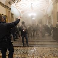 n this Wednesday, Jan. 6, 2021 file photo smoke fills the walkway outside the Senate Chamber as supporters of President Donald Trump are confronted by U.S. Capitol Police officers inside the Capitol i