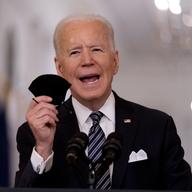 President Joe Biden holds up his mask as he speaks about the COVID-19 pandemic during a prime-time address from the East Room of the White House, Thursday, March 11, 2021, in Washington.
