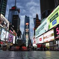 This March 20, 2020 file photo, shows a screen displaying messages concerning COVID-19, right, in a sparsely populated Times Square in New York.