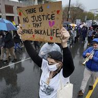 A demonstrator holds up a sign while marching during a protest Wednesday, April 21, 2021 in the Nubian Square neighborhood of Boston, a day after a guilty verdict was announced at the trial of former