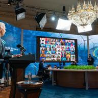 a man, joe biden, speaks at a podium behind to the side of him is a large screen with zoom callers and a board with a logo that reads leaders summit on climate