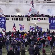 Crowds of rioters at the Capitol wave Trump 2020 flags and American flags.