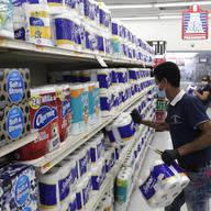 Jesus Padron wears a protective mask as he stocks shelves with toilet paper at the Presidente Supermarket during the new coronavirus pandemic, Tuesday, April 21, 2020.