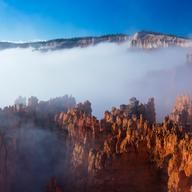 a layer of fog partially obscuring a majestic canyon