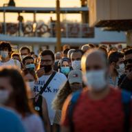 a crowd of people at sunset mostly wearing masks