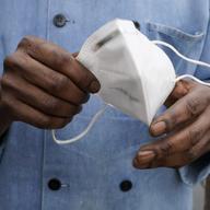 In this Friday, March 5, 2021 file photo, a restaurant worker holds his face mask in Biloxi, Miss. 