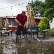 A worker cleans the outside area of Four Boys Ice Cream store during the passing of Tropical Storm Henri in Jamesburg, N.J., Monday, Aug. 23, 2021.