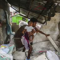 A woman carries her child as she walks in the remains of her home destroyed by Saturday´s 7.2 magnitude earthquake in Les Cayes, Haiti, Sunday, Aug. 15, 2021. 