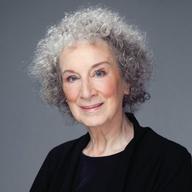 a headshot of a woman with gray curly hair and a black suit.