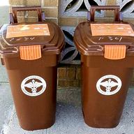 brown composting bins sit side-by-side on a sidewalk
