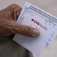 a hand holds a vaccine card.