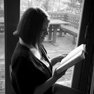 Rachel Held Evans reads a Bible in her home next to a sliding glass door. 