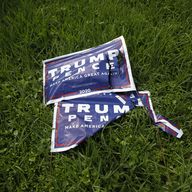 Two damaged Trump/Pence campaign signs lie on grass