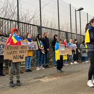 Protestors hold signs regarding Ukraine as they stand outside the security perimeter during a meeting of NATO defense ministers at NATO headquarters in Brussels, Wednesday, March 16, 2022.