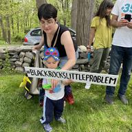 Marlena Fontes, one of the founders of Sunrise Kids, gives a sign to her 2-year-old son, 'Super' Nacho, during a protest at Larry Fink’s home.
