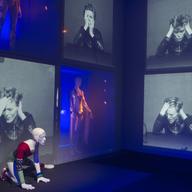David Bowie appears on a giant screen with various costumes he performed in.