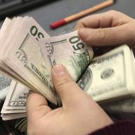 A woman counts U.S. dollar banknotes. This year, US inflation has hit record highs. 