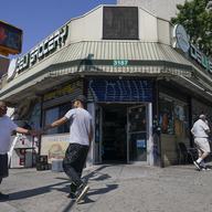 People walks in and out of a bodega in the Bronx section of New York, Friday, July 22, 2022. 
