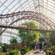 Model train tracks assembled inside a glass greenhouse