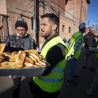 Church volunteers serve garlic bread to migrants camping outside the Sacred Heart Church in downtown El Paso, Texas, Sunday, Jan. 8, 2023.