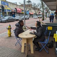 WNYC journalist interviewing a local resident outside a mall in Jamaica, Queens