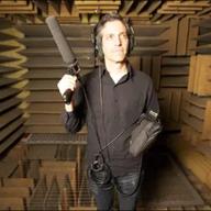 A man in a sound-proofed room holding a large microphone