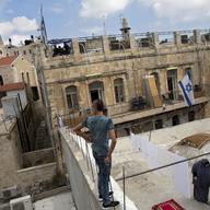 In this Saturday, Oct. 10, 2015 photo, a Palestinian woman takes down laundry on her balcony facing a Jewish seminary in Jerusalem's Old City Muslim Quarters. 