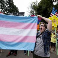 A supporter for the transgender community holds a trans flag in front of counter-protesters to protect attendees from their insults and obscenities at the city's Gay Pride Festival in Atlanta on Satur