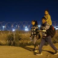 A migrant family from Peru walk towards a gate in the border fence after crossing from Ciudad Juarez, Mexico into El Paso, Texas, in the early hours of Thursday, May 11, 2023.