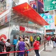 People standing in line at a glass booth with a red awning