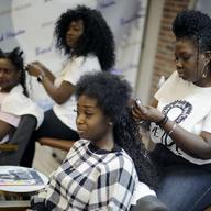Sisters Shelly Smith, back, and Glynnis Smith, right, braid hair for Bridget Dunmore, left, and Alicia McGee, front at their salon, Braid Heaven, Tuesday, Jan. 28, 2020 in Kansas City, Kan.