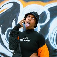 Artist Alexa Marie 'Lotus' Alerte is making funny facial gestures -- rolling her eyes back and sticking out her tongue. She is wearing a black shirt with 'Hello Kitty' on the front. 
