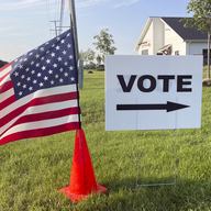 An American flag waves in the breeze next to a sign directing Ohioans to vote inside Tharp Sixth Grade School, Tuesday, Aug. 8, 2023 in Hilliard, Ohio.